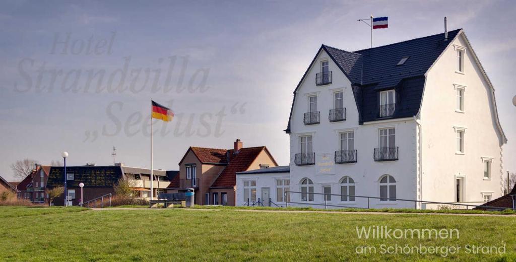 舍恩贝里耶海滩Strandvilla Seelust的一座大型白色房子,上面有两面旗帜