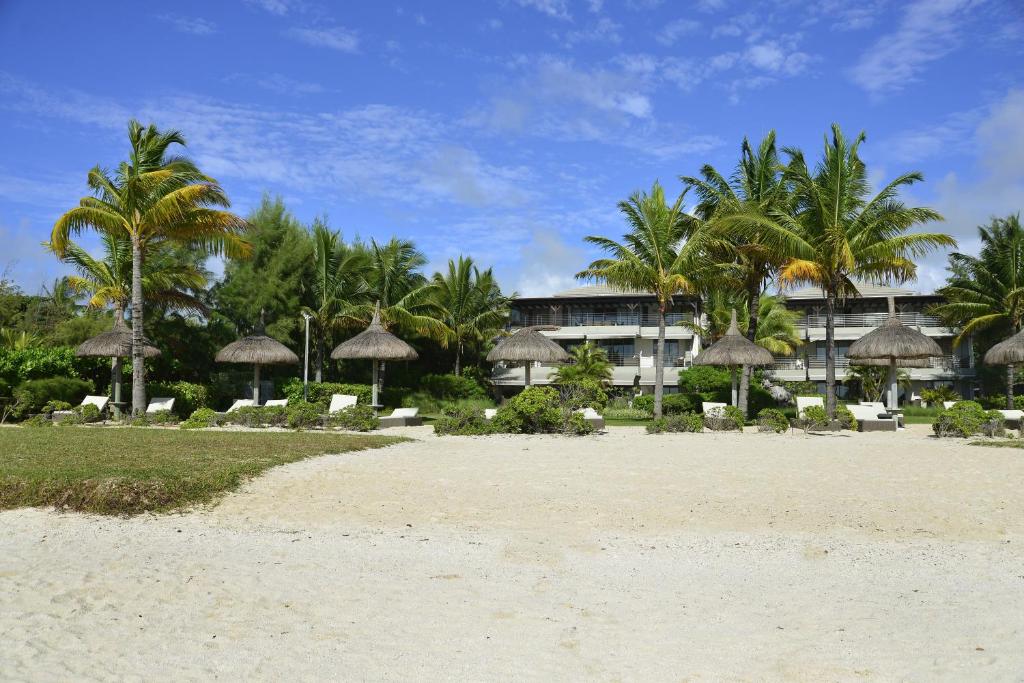 埃斯尼角Sablexotique的一片带遮阳伞和棕榈树的海滩和一座建筑