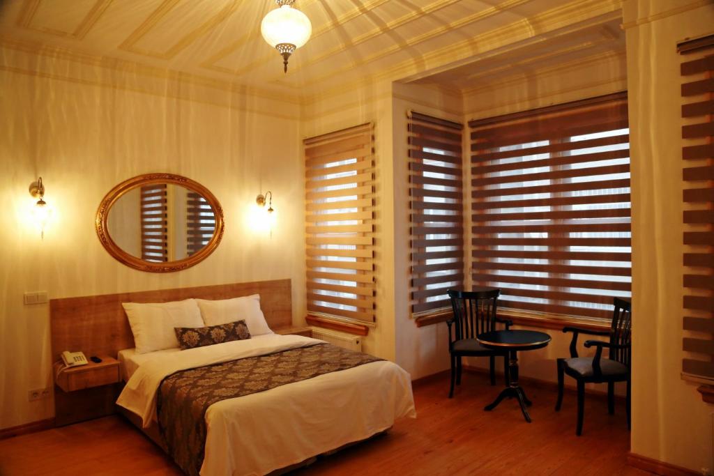 伊斯坦布尔Belizia Hotel的一间卧室配有一张床、一张桌子和一面镜子