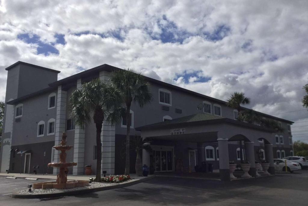 博尼塔斯普林斯Days Inn & Suites by Wyndham Bonita Springs North Naples的一座大型灰色建筑,前面有棕榈树