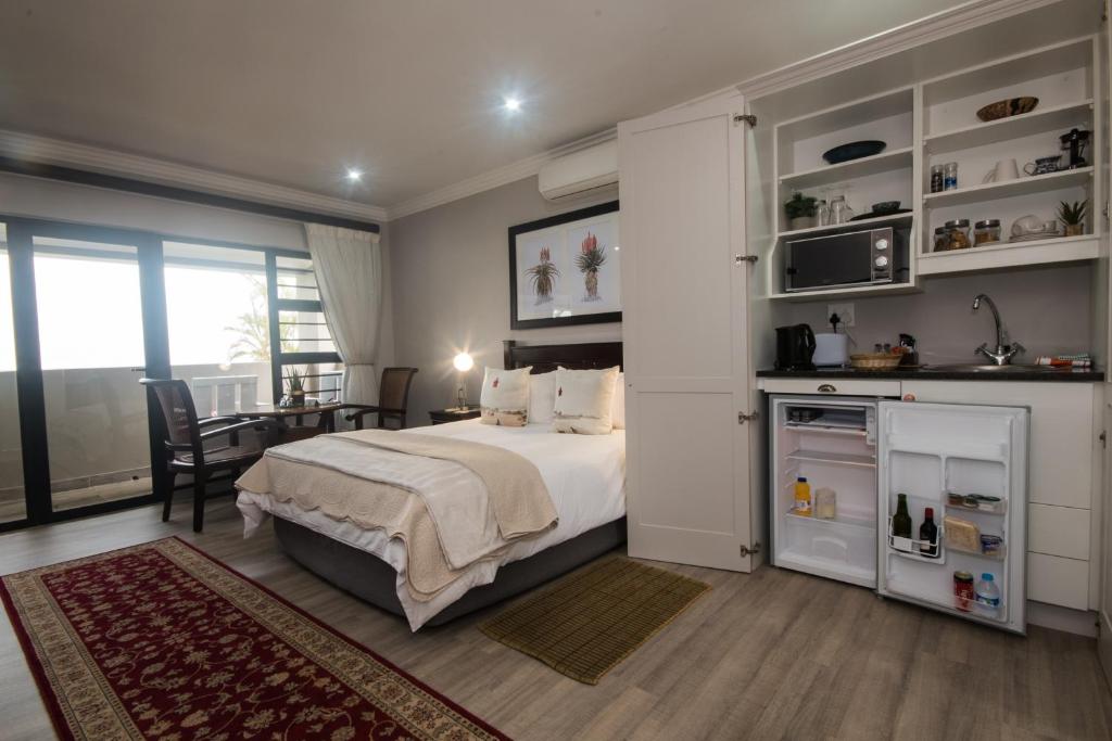 德班Hillside Guesthouse Umhlanga的一间卧室配有一张床、一间厨房和一张桌子
