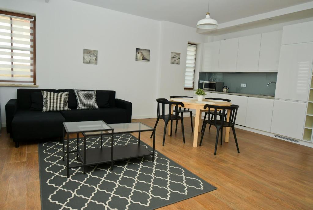 纳文丘夫Poduszka Apartamenty Zdrojowe的客厅配有黑色沙发和桌子