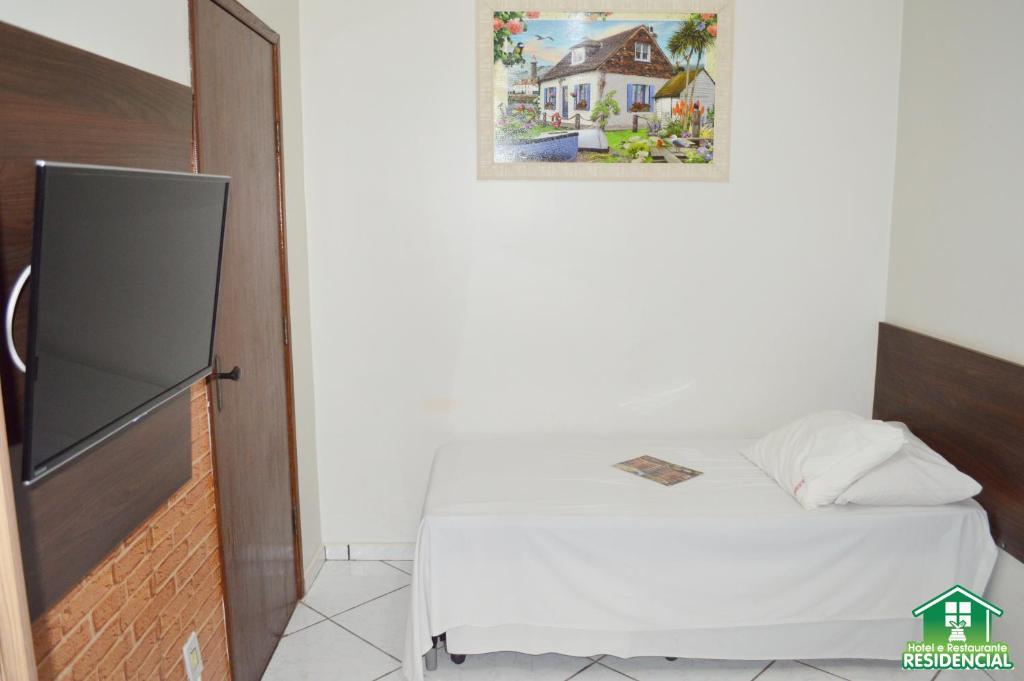 蒙蒂斯克拉鲁斯Hotel e Restaurante Residencial的一间小卧室,配有一张床和墙上的照片