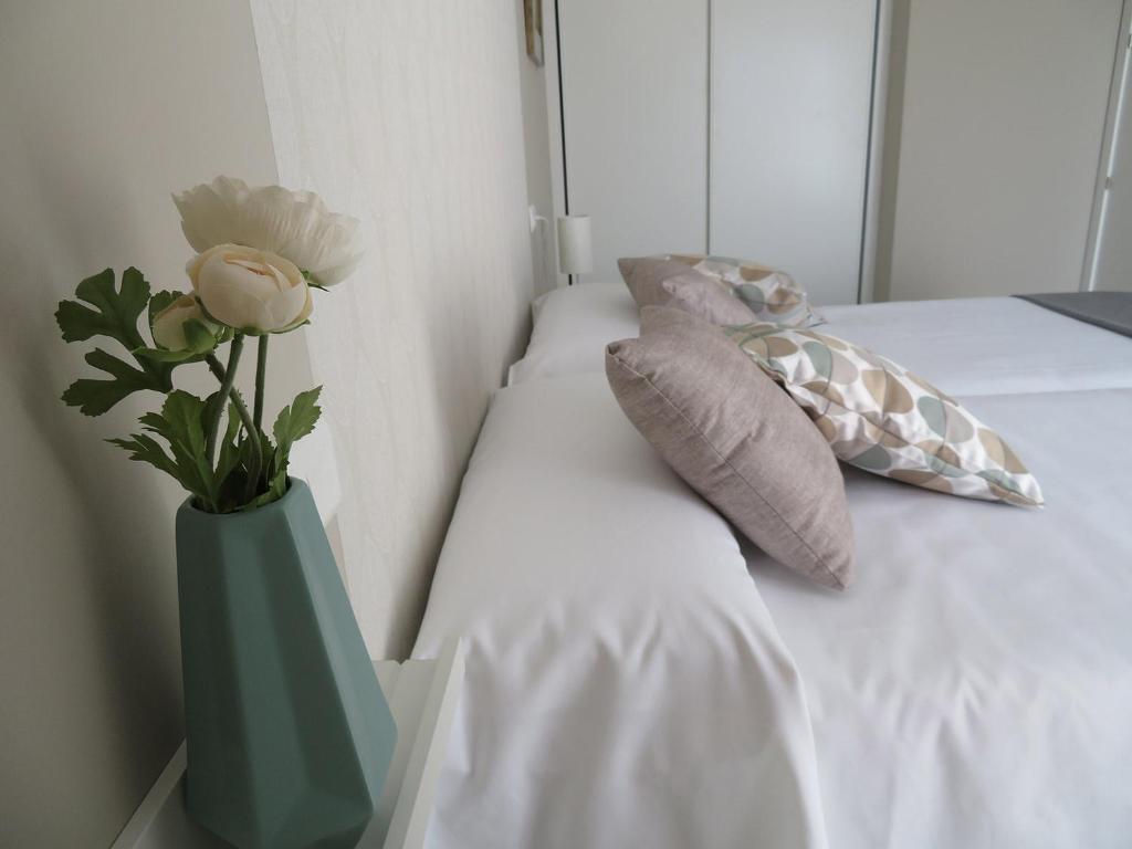 阿尔卡尼斯Alcañiz Flats II的绿花瓶,床上挂着鲜花