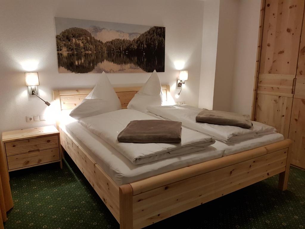 绍滕斯豪斯阿尔盘格伦旅馆的一间卧室配有一张带白色床单和枕头的木制床。