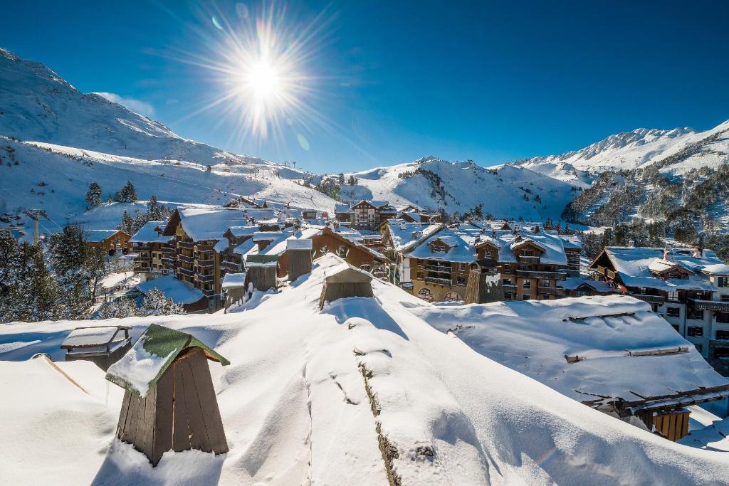 阿克1950Residence Arc 1950 Le Village - maeva Home的山中一个雪覆盖的村庄,阳光照耀着
