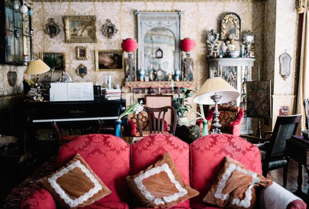 海斯廷斯圣本笃 - 维多利亚式住宿加早餐旅馆的客厅配有红色沙发和钢琴
