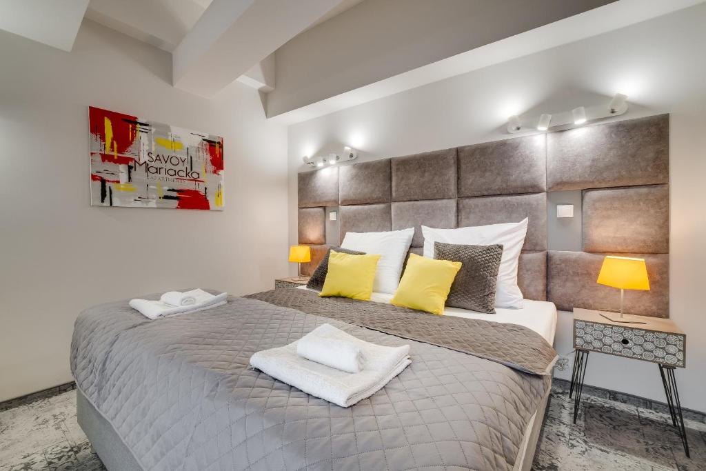 卡托维兹SAVOY Mariacka Apartments的一间卧室配有一张带黄色枕头的大床