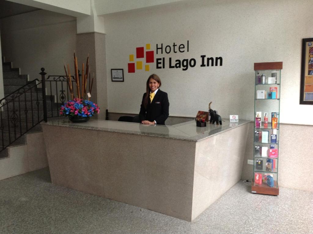 波哥大Hoteles Bogotá Inn El Lago Country的坐在旅馆里的一个柜台上的女人