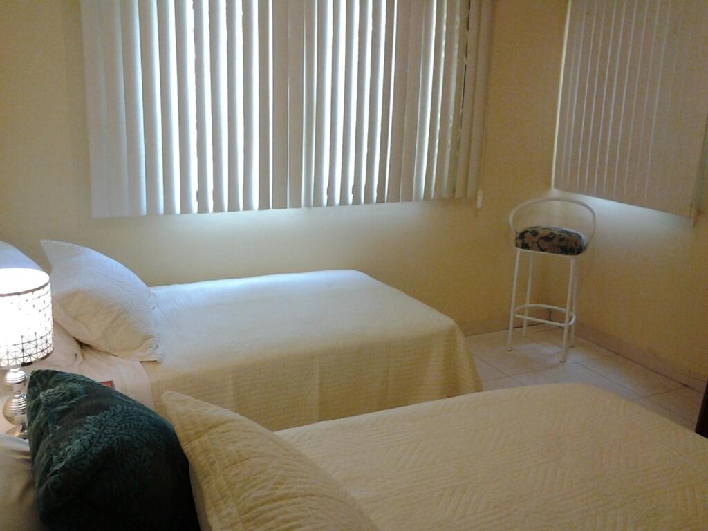 瓜亚基尔拉罗莎套房住宿加早餐旅馆的一间卧室设有两张床、一个窗口和椅子