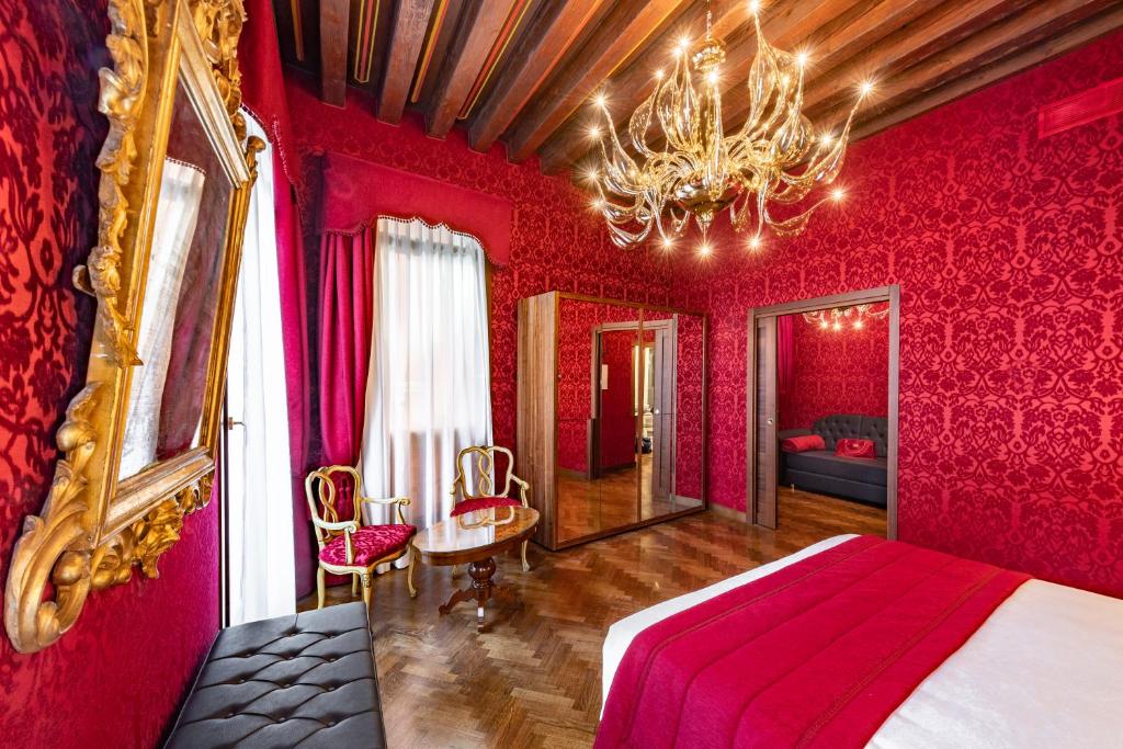 威尼斯Palazzo San Lorenzo的红色卧室配有一张床和一个吊灯
