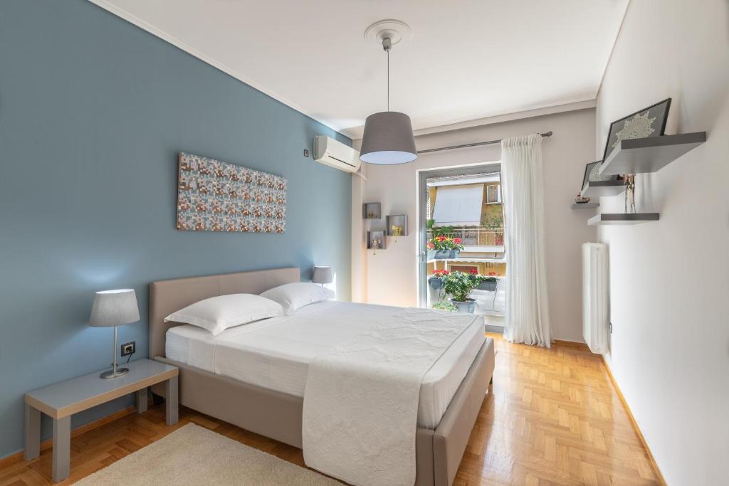 雅典Tranquil Central Apt, behind Athens Caravel Area的卧室配有白色的床和蓝色的墙壁