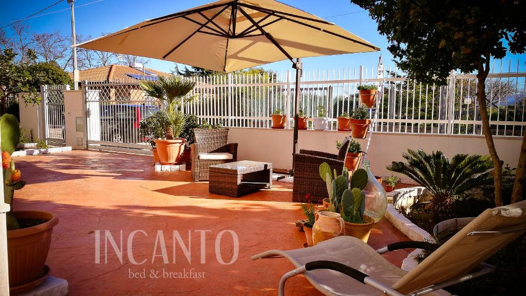 莱西纳Incanto b&b的一个带遮阳伞、椅子和植物的庭院