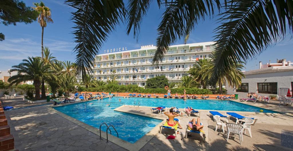 圣安东尼奥热带酒店的酒店拥有游泳池,游泳池里的人坐在椅子上