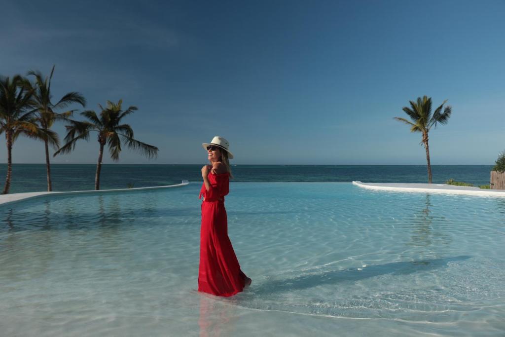 吉汶瓦Zanbluu Beach Hotel的身穿红色衣服的妇女站在水里