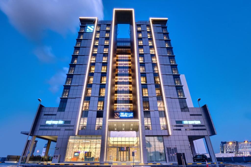 迪拜The S Hotel Al Barsha的一座高大的建筑,灯火通明