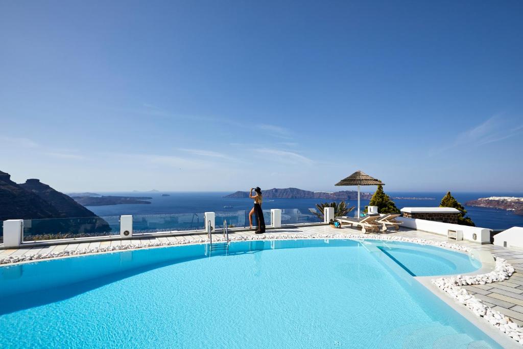 易莫洛林Santorini Princess Spa Hotel的一位女士站在游泳池旁边