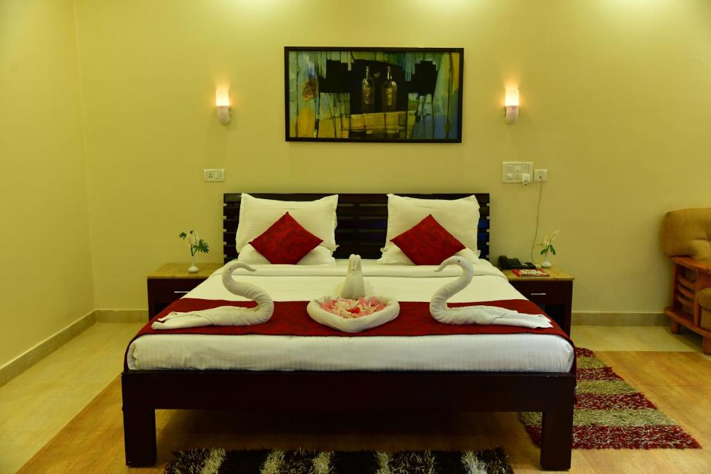马迪凯里KSTDC Hotel Mayura Valley View Madikeri的一间卧室配有一张带红色和白色枕头的大床