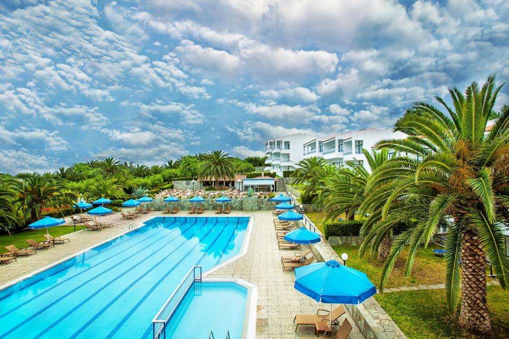 佩科霍里Xenios Port Marina Hotel的一个带蓝伞和棕榈树的游泳池