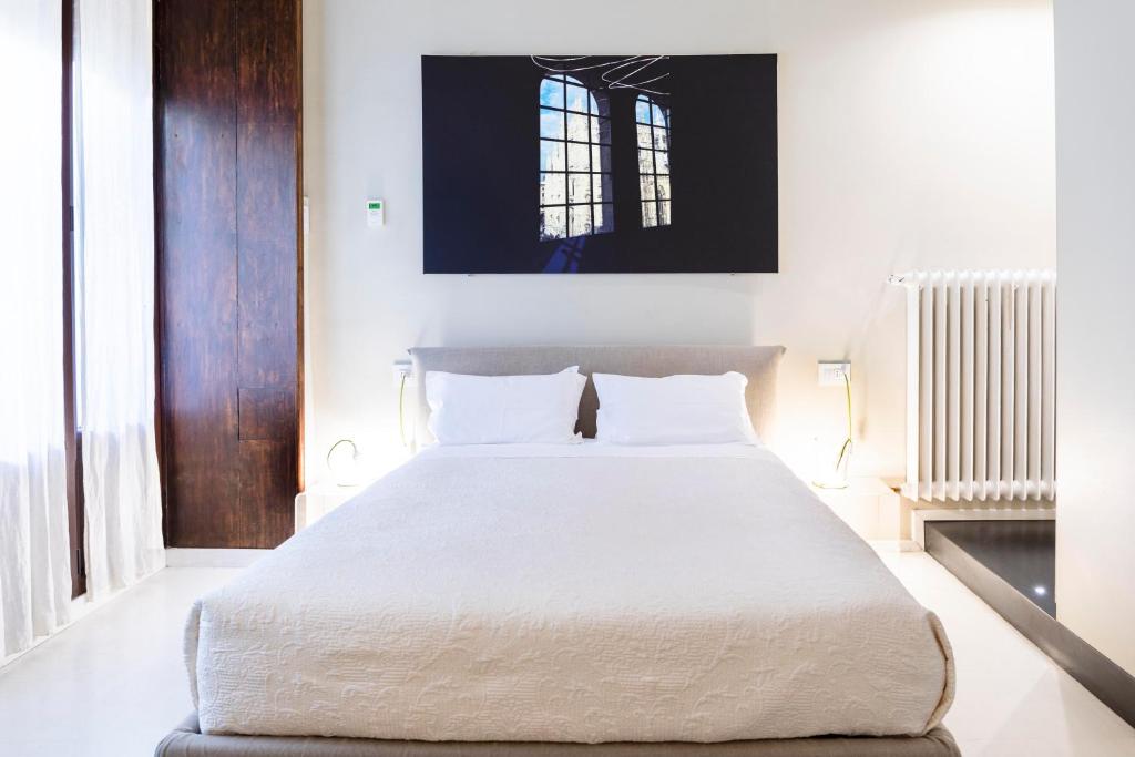 米兰BC MAISON bed&cafe Milano的一间卧室配有一张带白色床单的大床