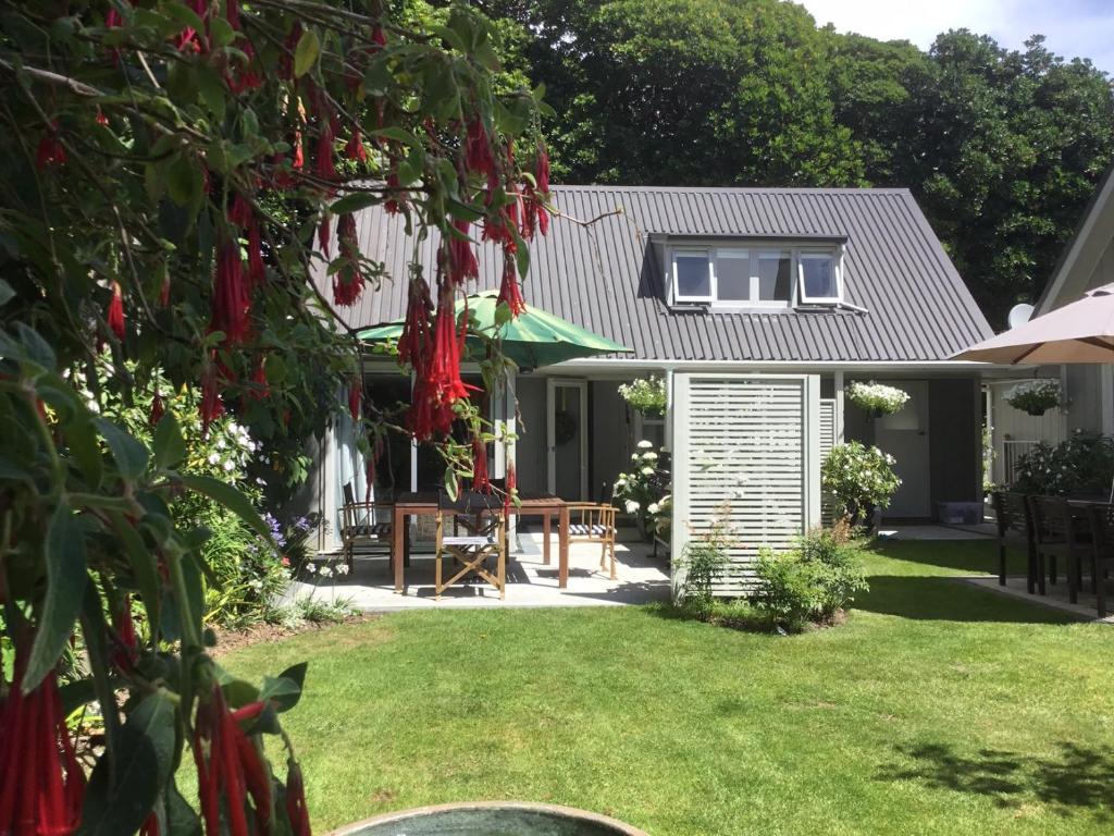 怀卡奈Sunny Glen Cottage的一座带红色鲜花的花园的房子
