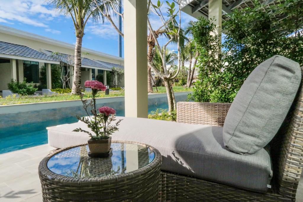 普吉镇CRAFT Resort & Villas, Phuket Town的一张柳条椅,坐在带玻璃桌的庭院