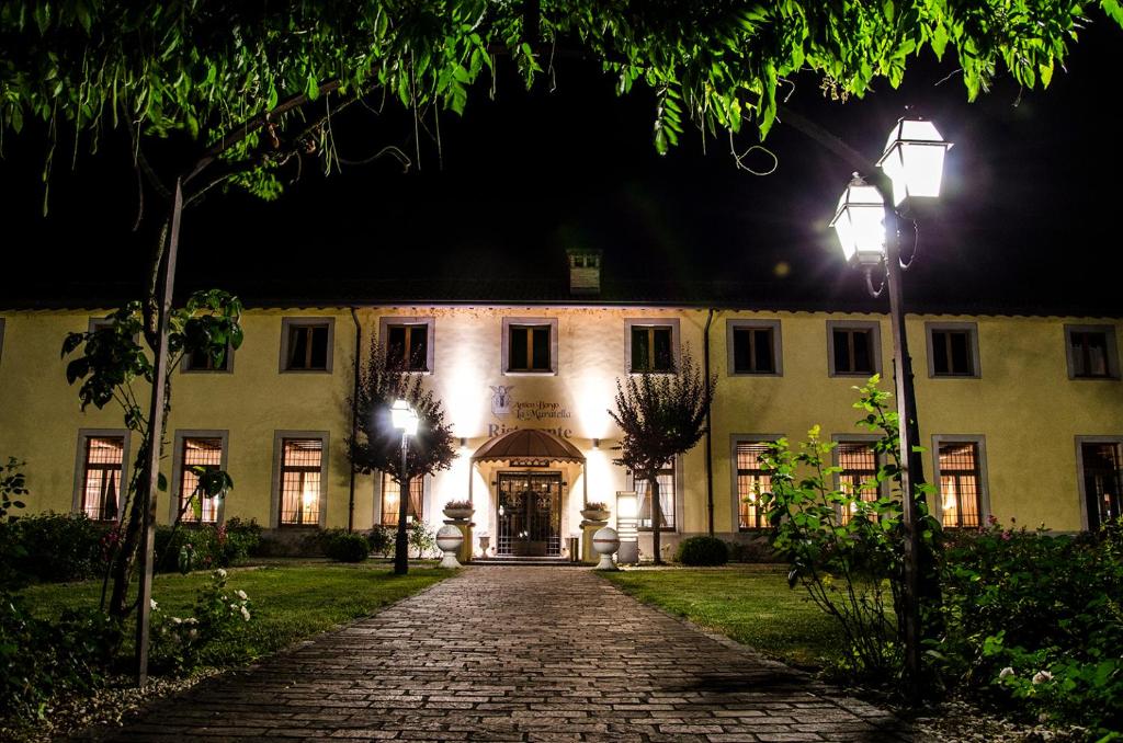克罗诺奥赛里Bes Hotel Bergamo Cologno al Serio的一座晚上有鹅卵石车道的建筑