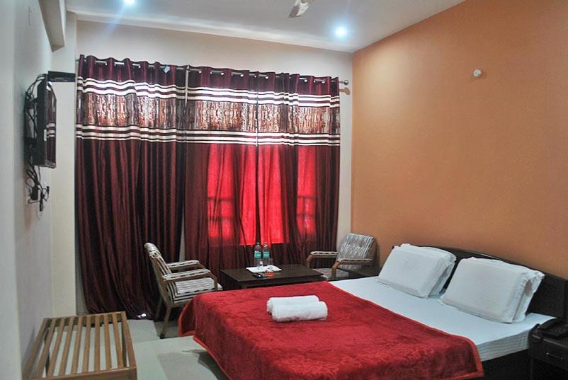 达兰萨拉Mountain and Moon, Dharamkot的一间卧室配有一张带红色毯子的床和窗户。