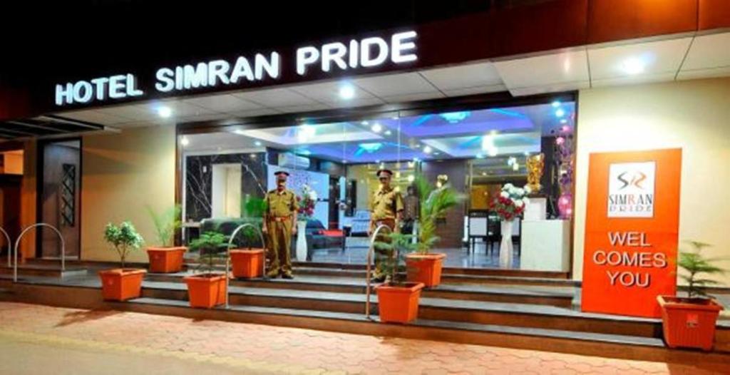 赖布尔Hotel Simran Pride, Raipur的一座建筑前面有两个人的酒店