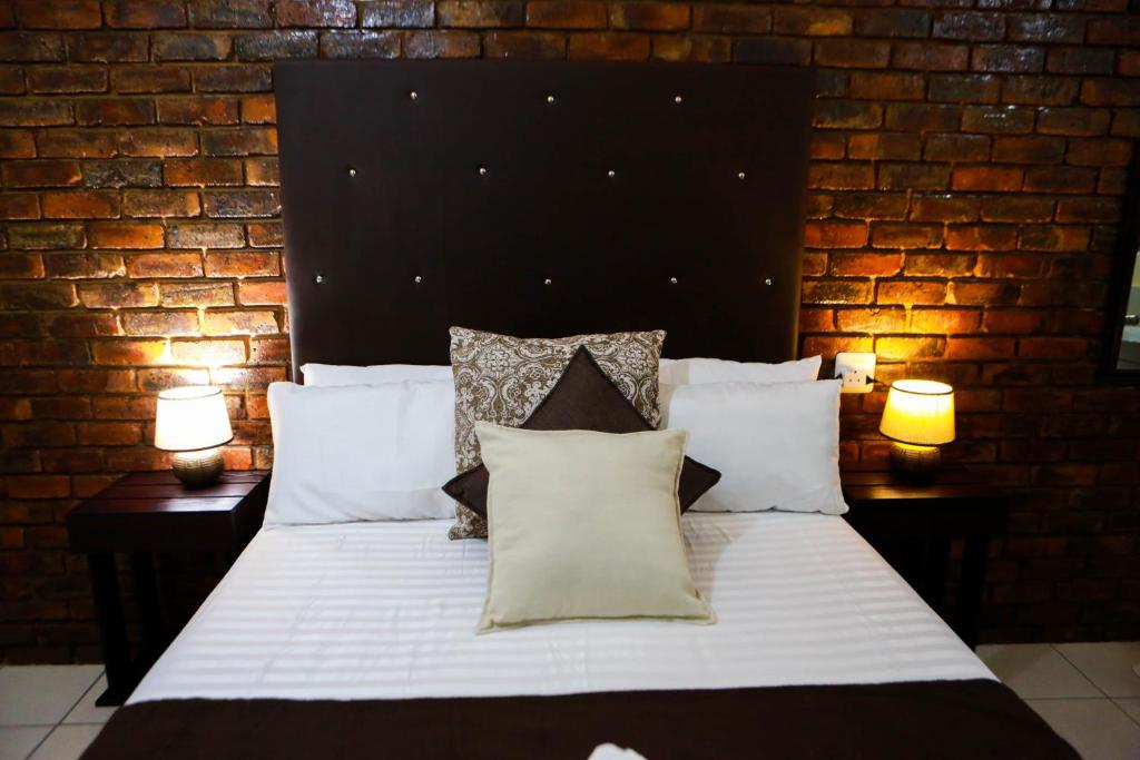 伯格斯堡Gracious Lodge的卧室配有一张白色大床和砖墙