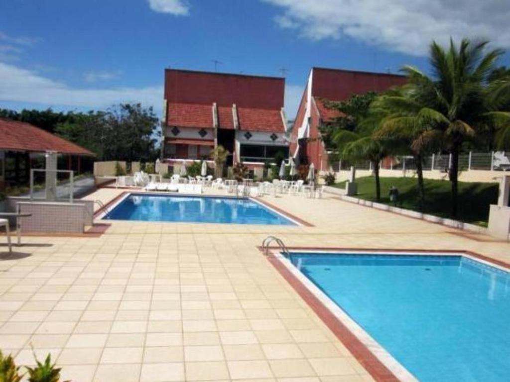 瓜拉派瑞Village dos Pássaros Apartamento的庭院内的大型游泳池,带房子