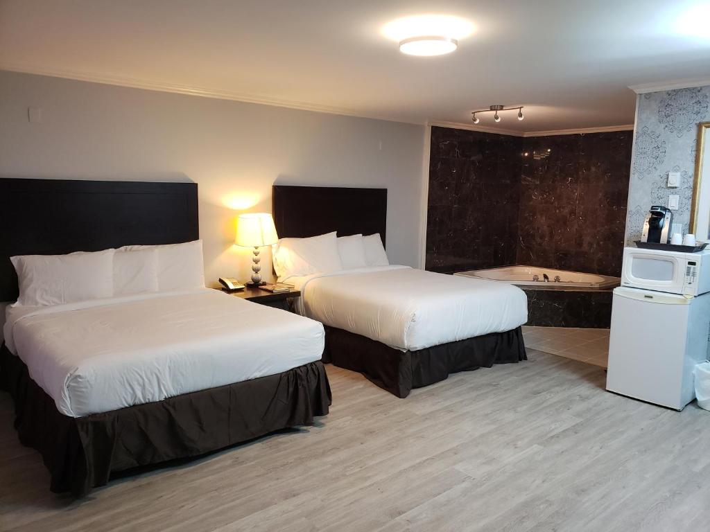 康沃尔Regency Inn & Suites的酒店客房设有两张床和浴缸。