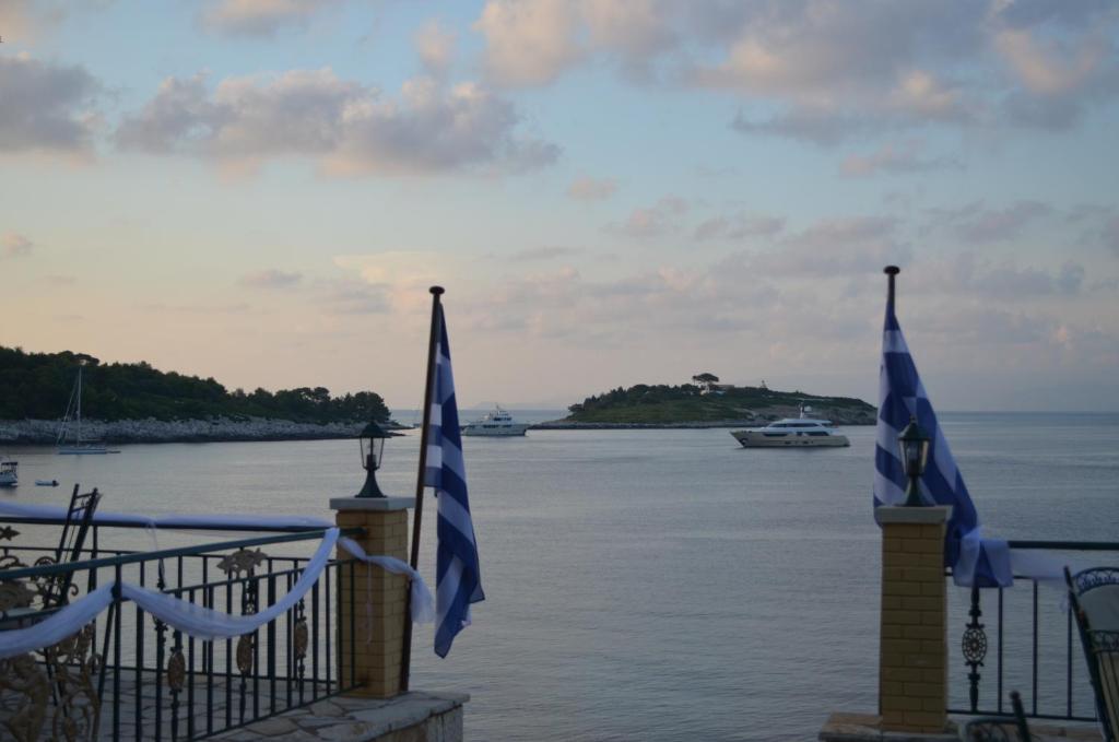 盖奥斯Margina Residence Hotel的水边围栏上两面旗帜,有船