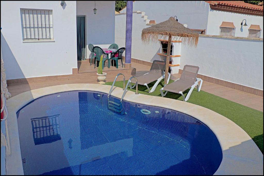 科尼尔-德拉弗龙特拉Chalet Muelle Pesquero 65的一个带椅子的庭院和房子的游泳池