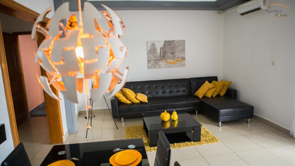 Odza IINandy's home的客厅配有黑色沙发和黄色枕头