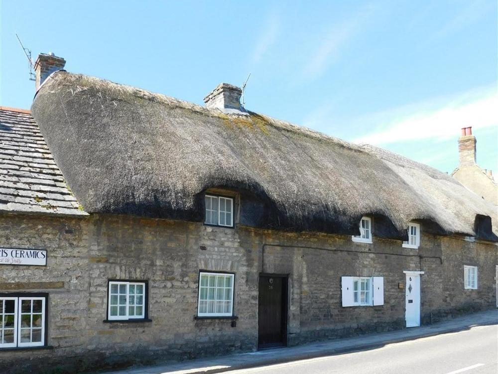 科夫堡Farrier's Lodge的一座带茅草屋顶的古老石头建筑
