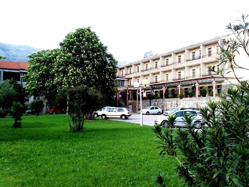 特雷比涅莱奥塔尔酒店的绿色田野前有车辆停放的建筑