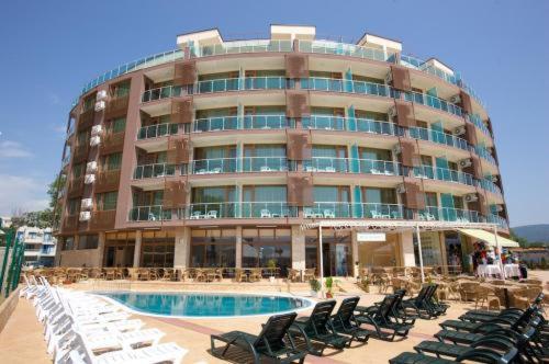 阳光海滩Briz Beach apartments - section B的一座带椅子的大型建筑,前面设有一个游泳池