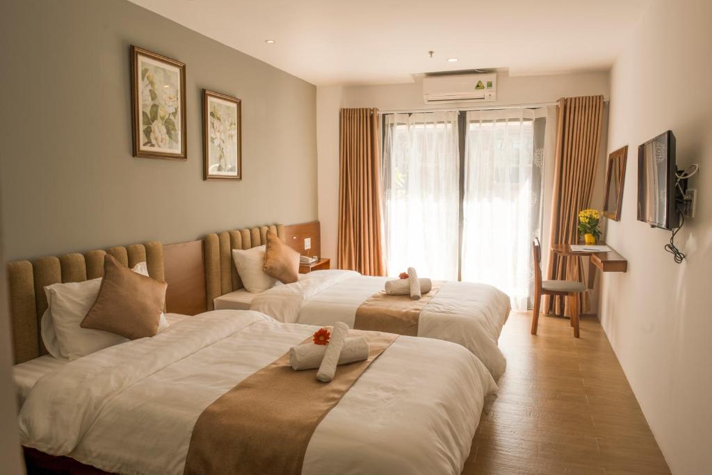 顺化Gardenia Hue Hotel的一间卧室设有两张床和窗户。