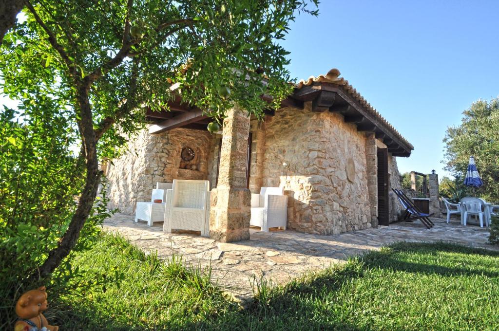 玛丽娜迪曼卡维萨Trullo Dei Beneficati by Salento Affitti的一座石头建筑,在院子里有白色家具