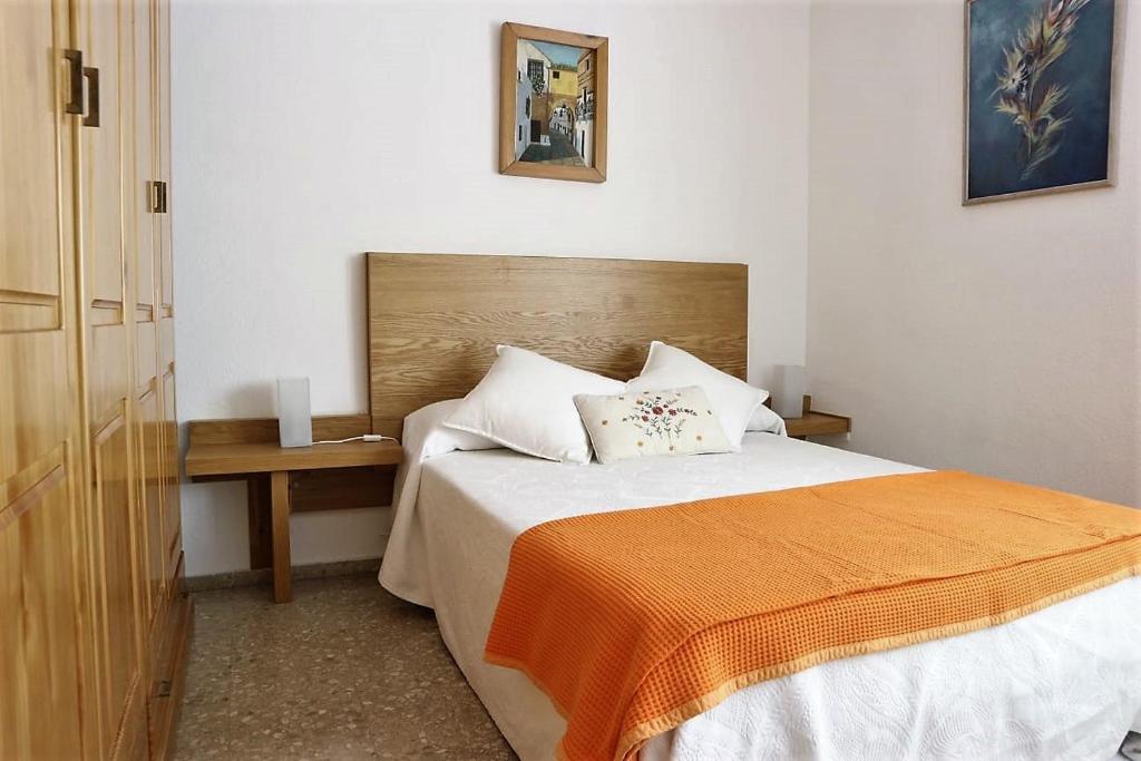 科尔多瓦雷梅迪奥斯公寓的一间卧室配有一张带橙色毯子和桌子的床