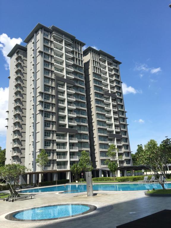 古晋OHANA Sky Villa Residences的一座大型公寓楼,前面设有一个游泳池