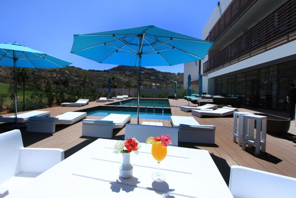 胡塞马绍阿尼酒店（胡塞马湾）的一个带桌子和遮阳伞的庭院和一个游泳池