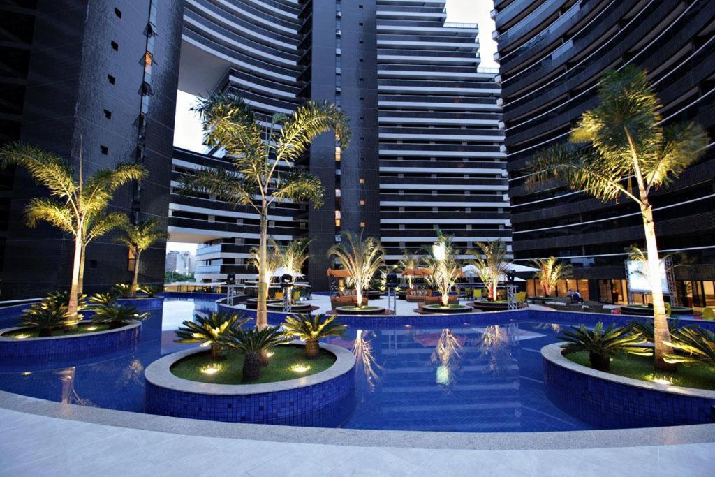 福塔莱萨Landscape Residence by Escala Imóveis的一座棕榈树环绕的游泳池,位于高楼前