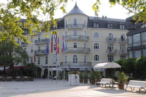 巴登-巴登豪斯莱歇特酒店的前面有旗帜的大型白色建筑