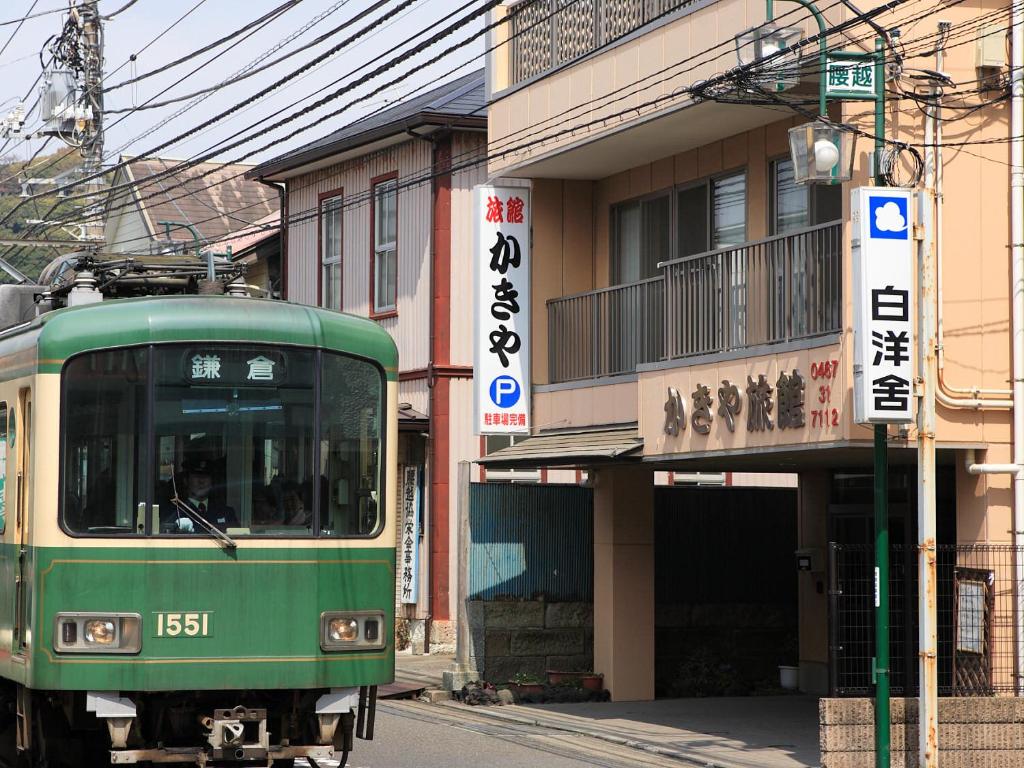 镰仓市垣屋日式旅馆的沿着大楼旁边的街道行驶的绿色火车
