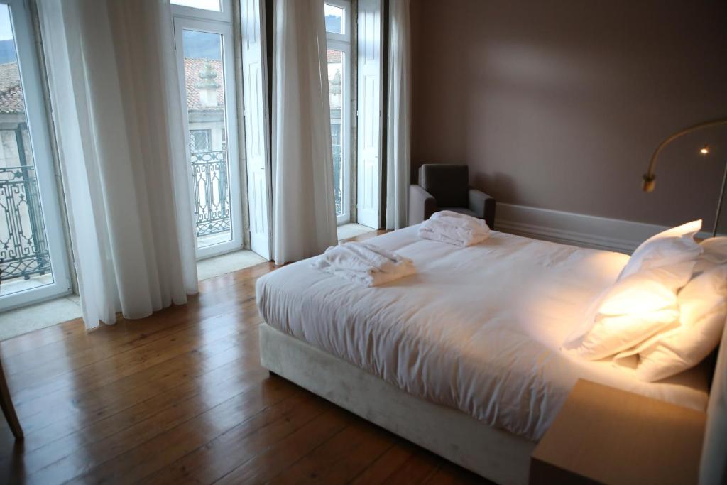 拉梅戈Muralha Charm House的卧室设有白色的床和大窗户
