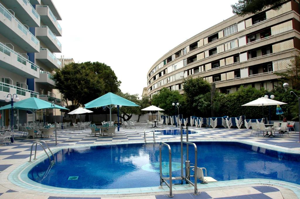萨洛圣莫妮卡海滩酒店的一座带椅子和遮阳伞的游泳池位于一座建筑旁边