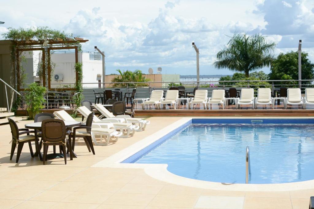 恩卡纳西翁De la Trinidad Hotel的一个带椅子和桌子的游泳池