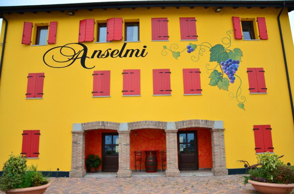 帕拉佐罗德罗斯泰尔拉迪安塞尔米农家乐的黄色的建筑,有红色的窗户和标志